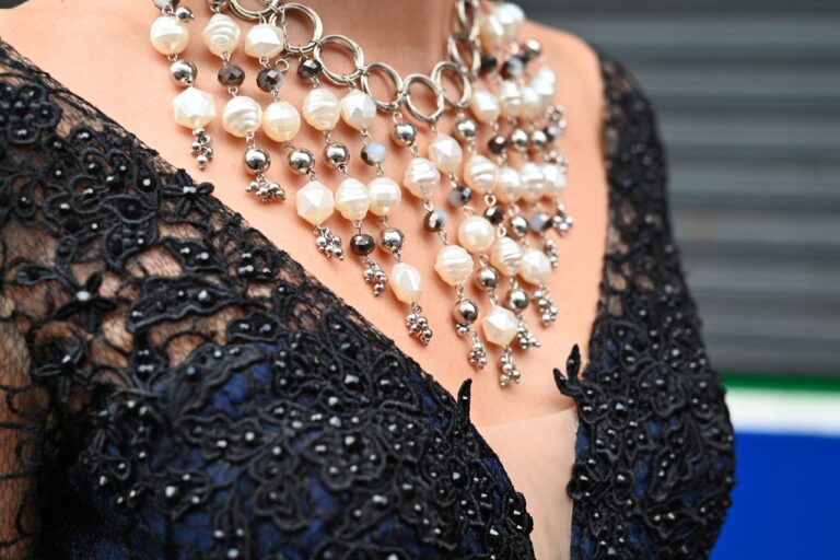 Detailed shot of an intricate pearl necklace on a black lace dress for fashion and accessory focus.