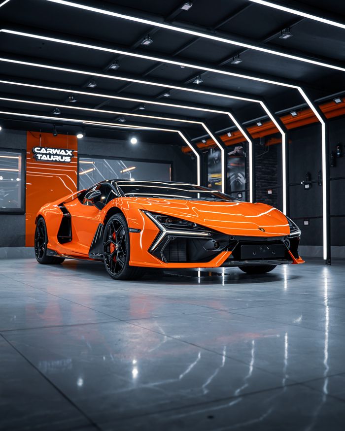 Sleek orange sports car showcased in a cutting-edge dealership in Ankara, Türkiye.